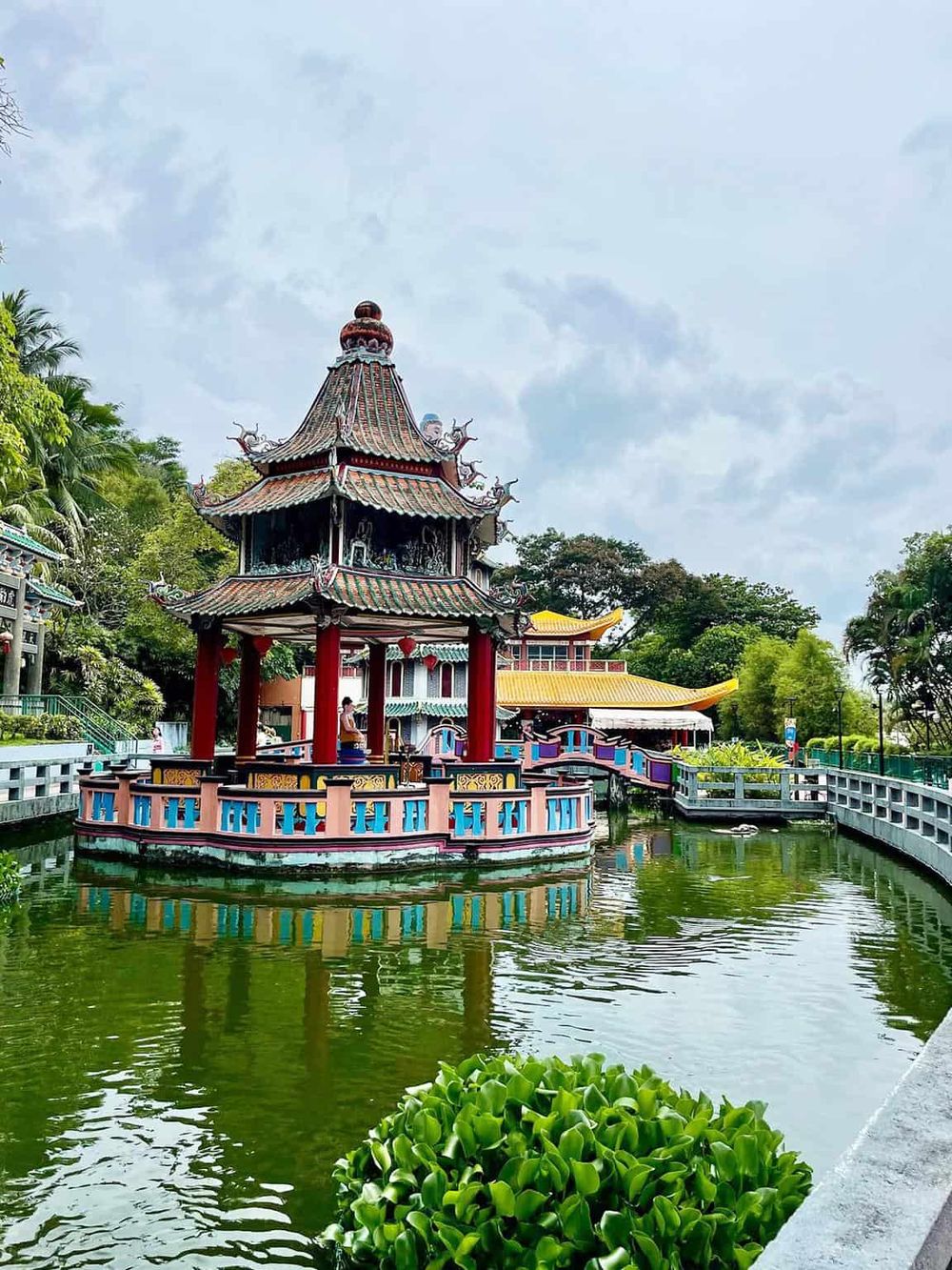 Colorful Chinese pagoda with water reflection, lush greenery, and garden landscape at Quest for Directions.