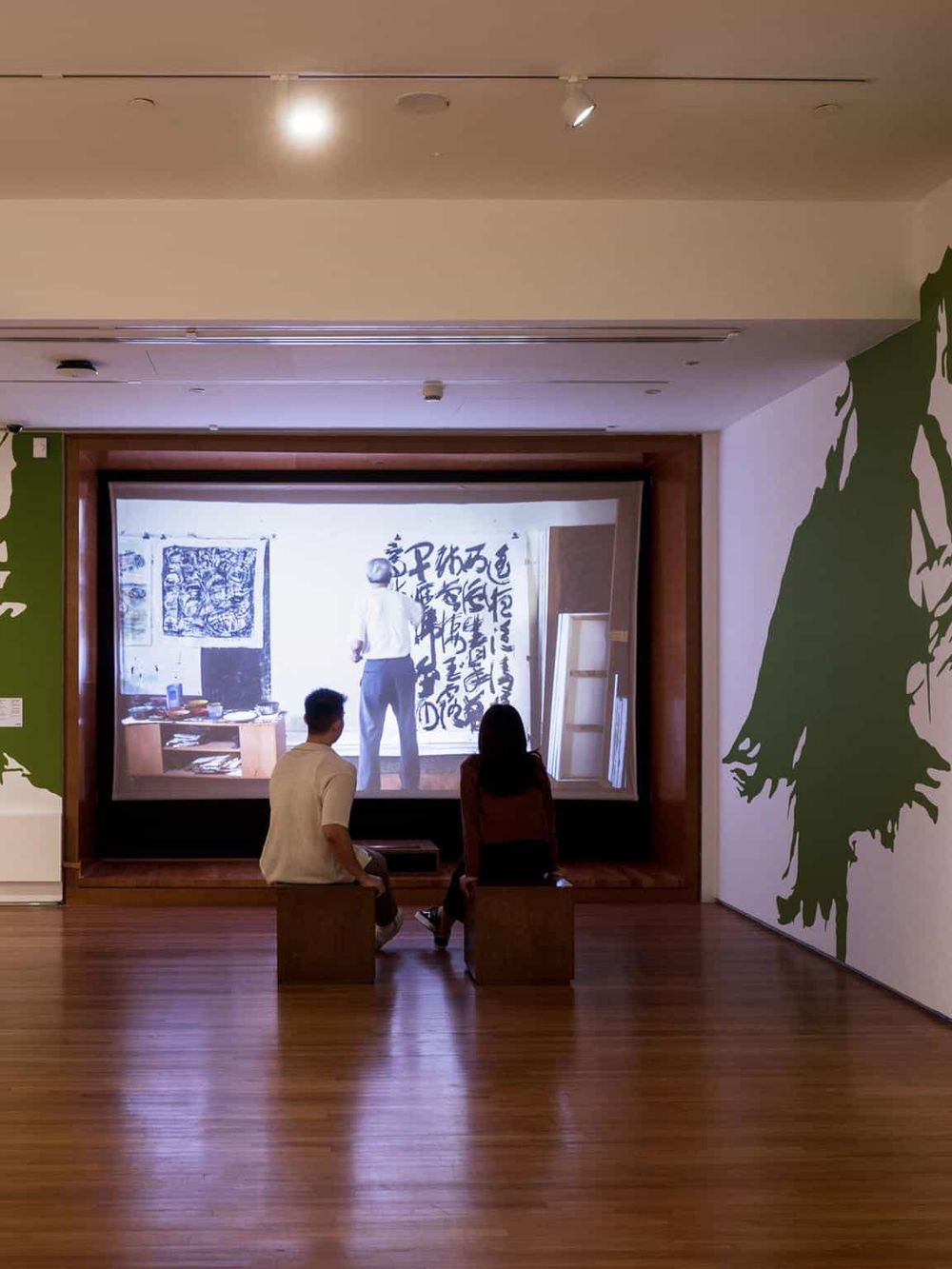 1. People watching an art presentation on a large screen in an art gallery or museum.