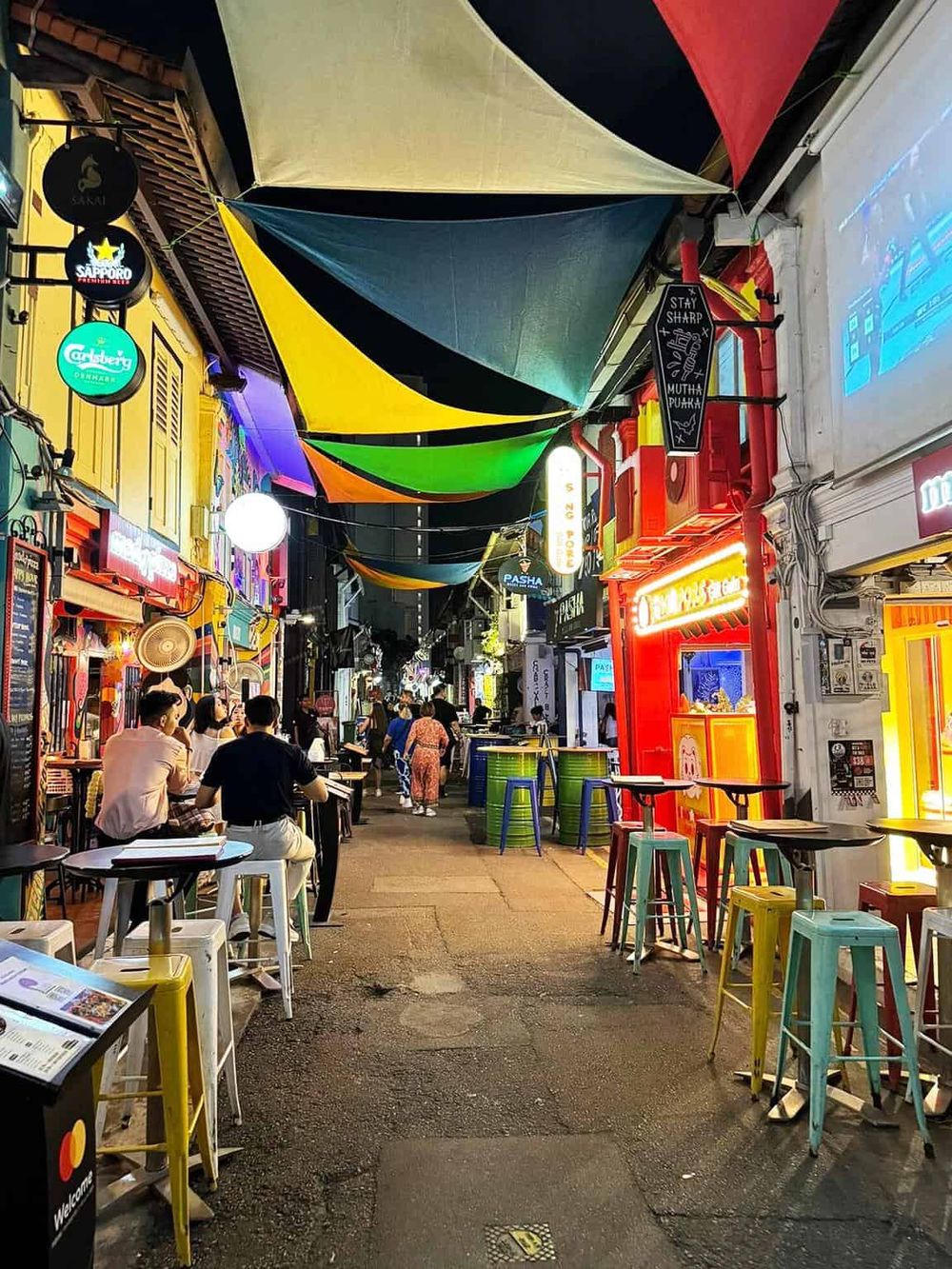 Colorful nightlife street with vibrant bars and restaurant signage, showcasing lively street cuisine scene.