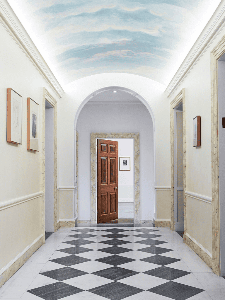 Elegant building corridor with marble flooring, doorways, and artwork, spotlighting QuestForDirections navigation solutions.