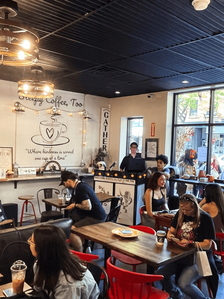 Coffee shop interior with customers enjoying beverages and a barista at the counter, cozy cafe setting, bright natural light from windows.