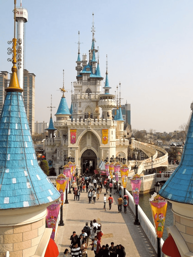 Colorful fairy tale castle at a theme park with visitors exploring the area.