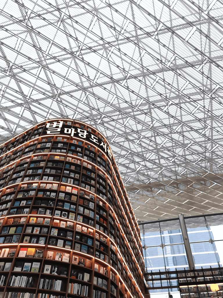 Endless bookshelves in a modern library with glass ceiling and architecture, QuestForDirections.
