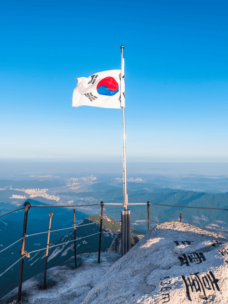 South Korea national flag on mountain peak with scenic landscape background.