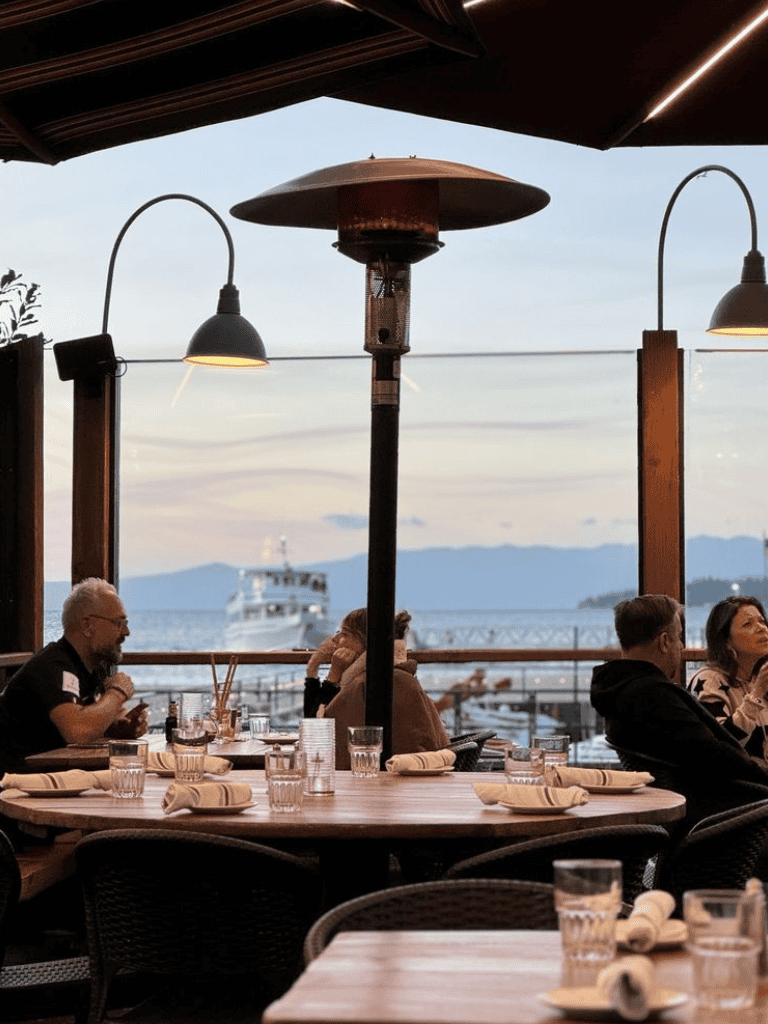 Cozy waterfront dining with ocean view, modern outdoor restaurant setup at sunset.