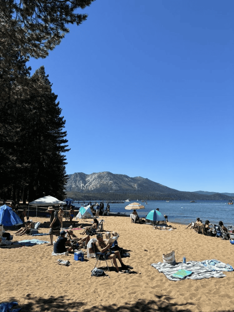 Beach with people relaxing, umbrellas, and mountains in the background for travel and vacation SEO.