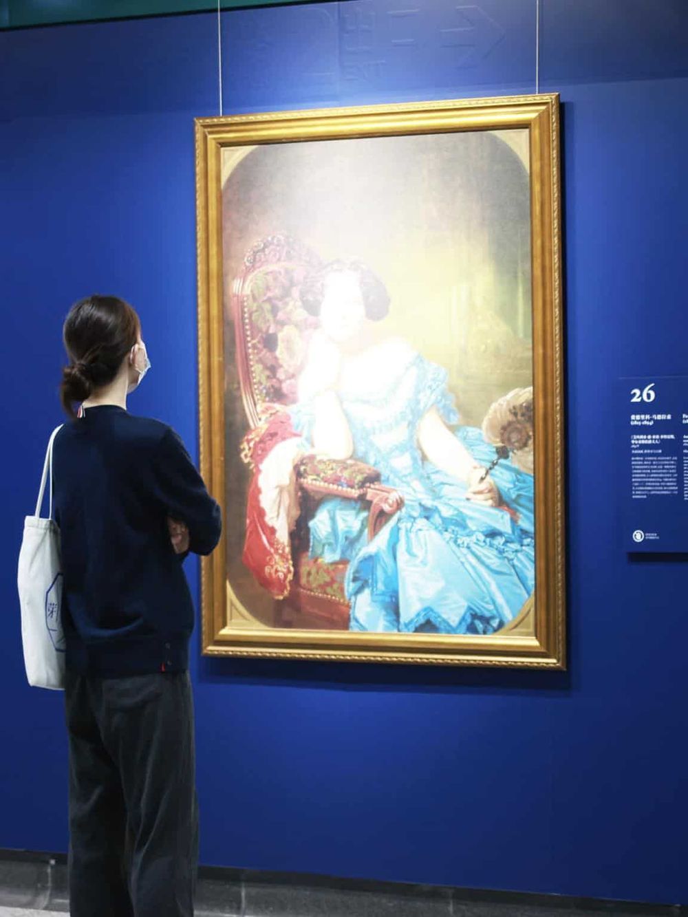 Elegant woman viewing classic portrait at art museum, cultural experience, art appreciation.