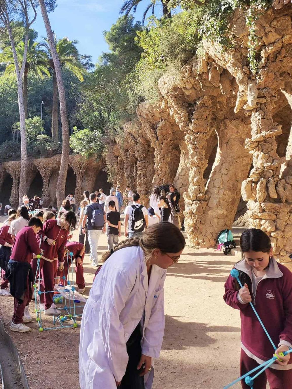 Vibrant outdoor scene with students and teachers exploring nature at Park Güell in Barcelona, highlighting educational and cultural experiences.