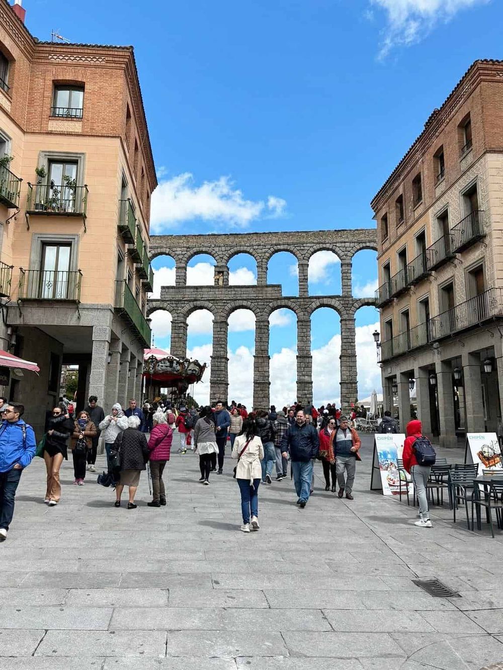 Ancient Roman aqueduct in Girona, Spain, with people exploring the historic site and vibrant city atmosphere.
