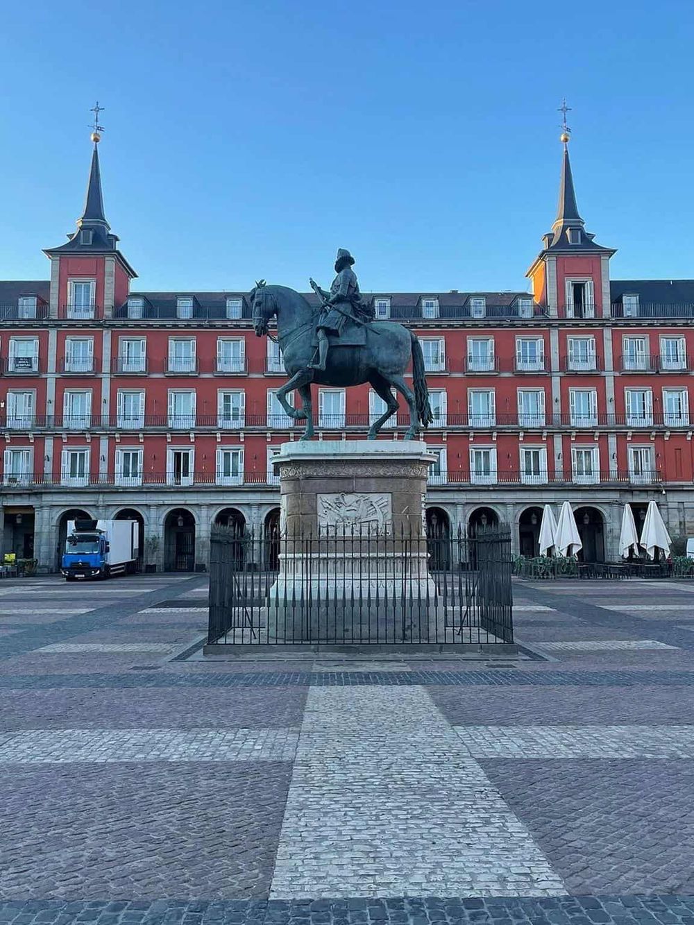 Historic plaza with statue of a regal figure on horseback, surrounded by colorful European-style buildings.