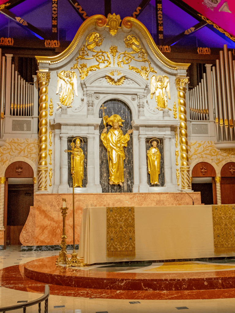 Intricate Catholic altar with golden statues and baroque design, altar inside a church, religious worship space, sacred Catholic architecture.