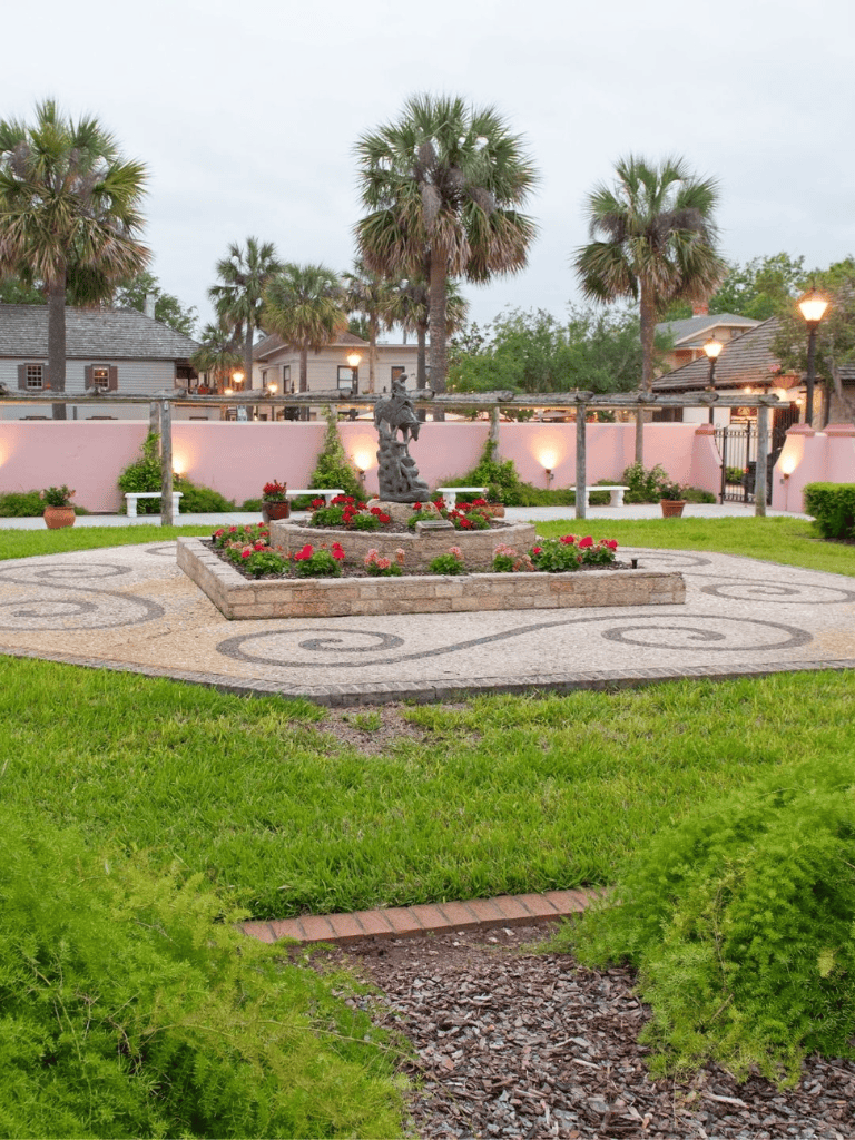 Colorful garden with palm trees, decorative fountain, and cozy outdoor seating area at QuestForDirections.