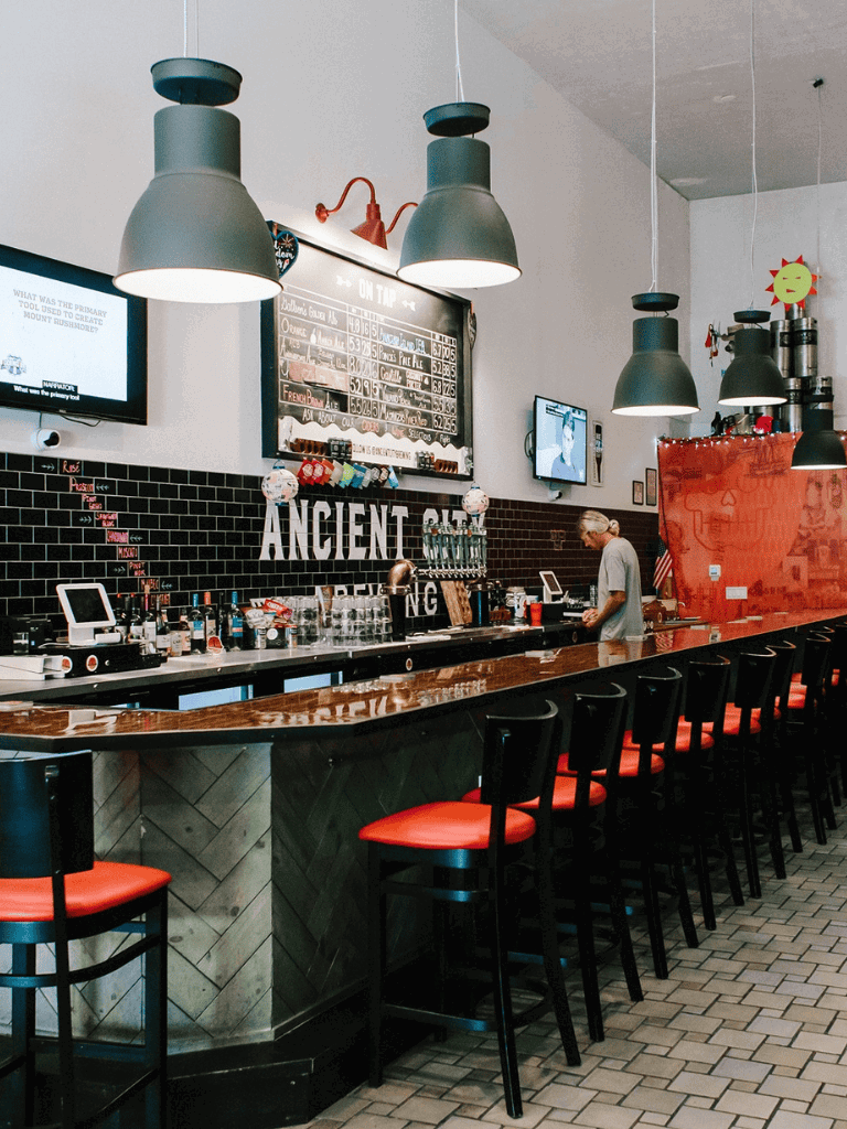 Bar interior at QuestForDirections restaurant with black tiled walls and modern lighting.