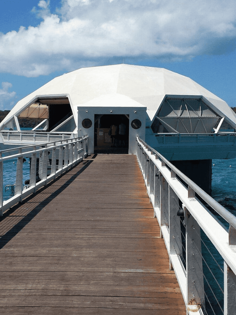 Modern geodesic dome on water with dock access, innovative architecture, and scenic ocean views.
