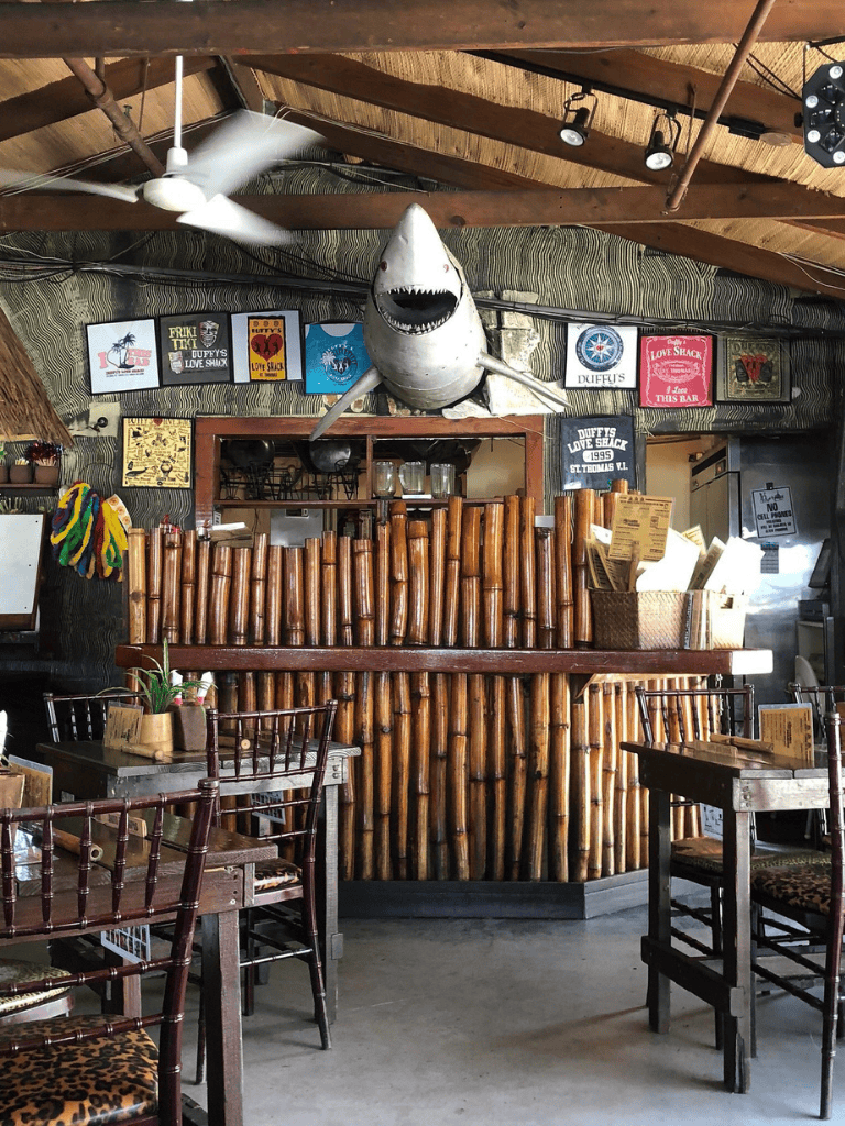 Shark decoration hangs above bamboo bar at tropical restaurant.