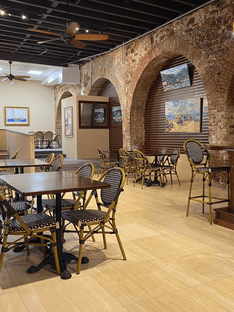 Charming restaurant interior with rustic brick arches, maritime artwork, and cozy seating for dining and events.