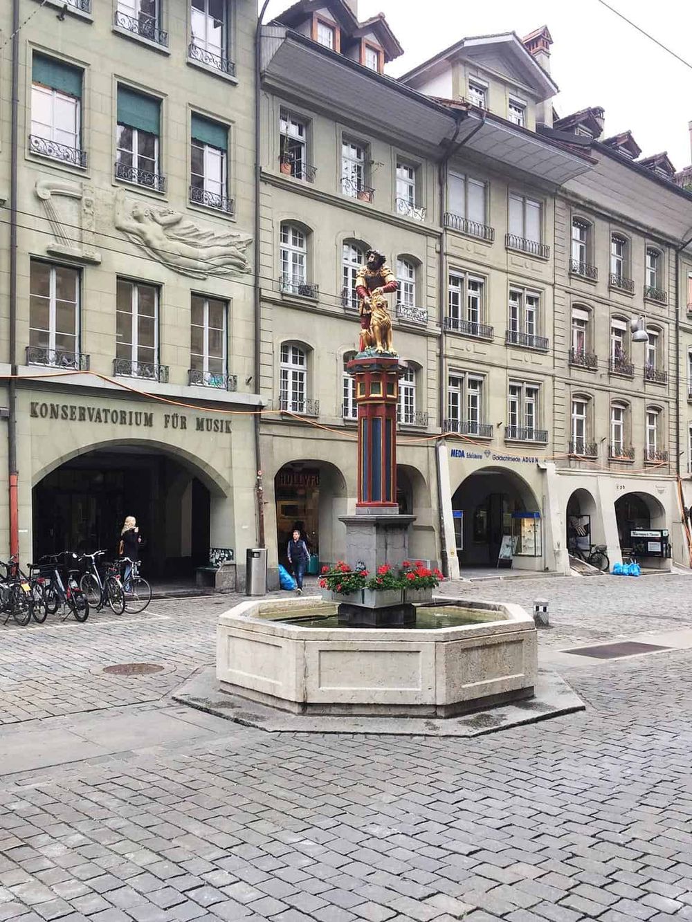 Vibrant city square with historical architecture, a decorative fountain, and colorful statues, perfect for exploring Zurich's culture.