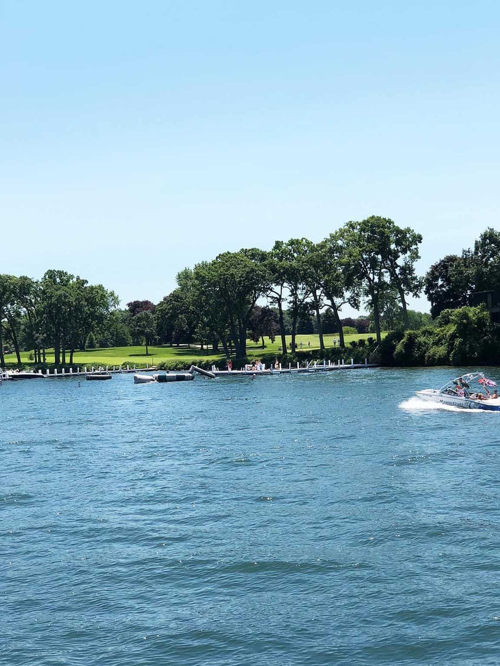 Serene water view at QuestForDirections lakeside with boats and lush green park scenery.