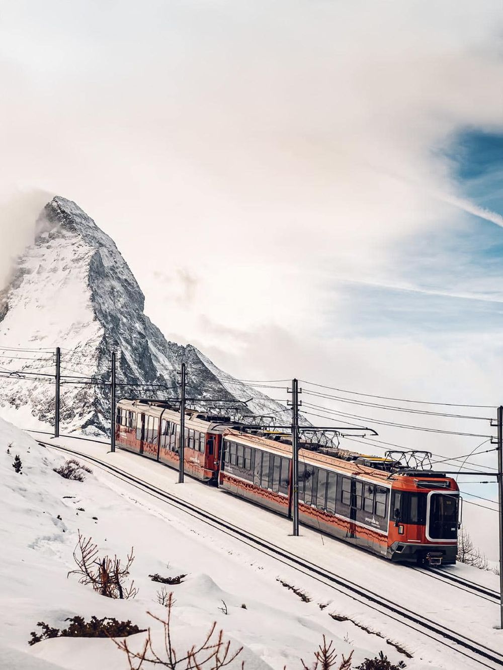 Snow-covered mountain with modern train on scenic mountain railway in winter, highlighting travel and adventure.