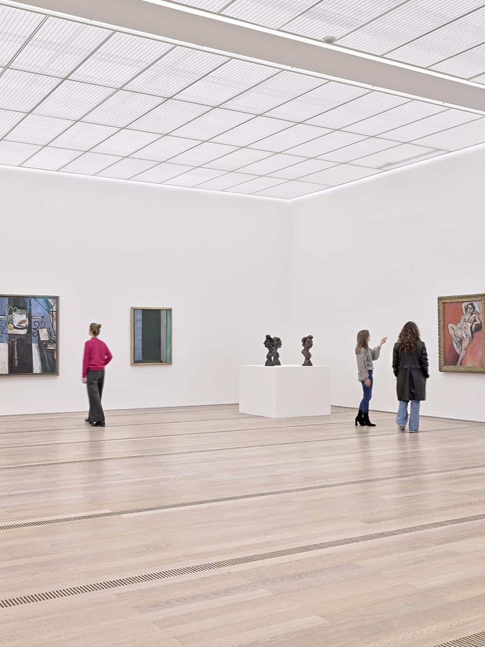 Modern art gallery interior with visitors viewing artwork and sculptures.