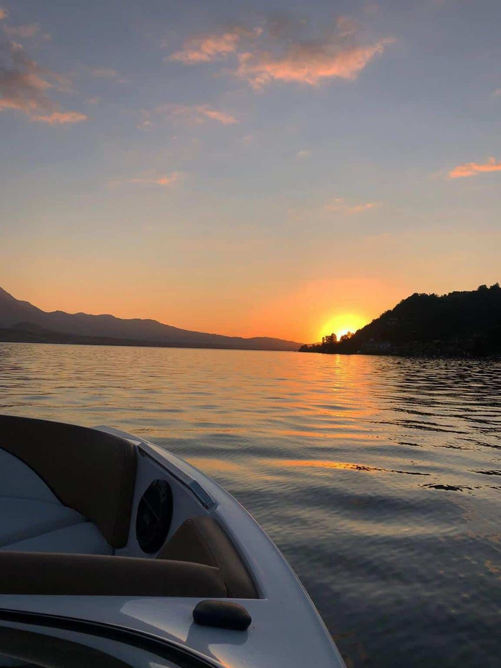 Serene sunset over calm lake with boat in foreground, perfect for tranquility and navigation.
