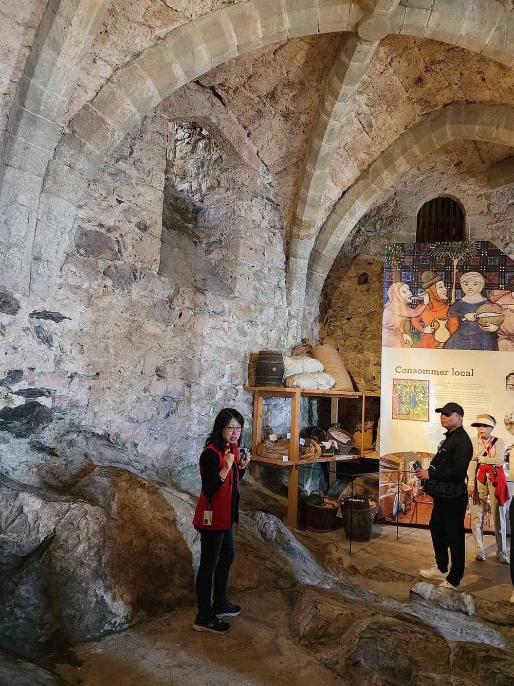 Ancient stone arch cave with museum exhibit and visitors, showcasing historic architecture and cultural displays.