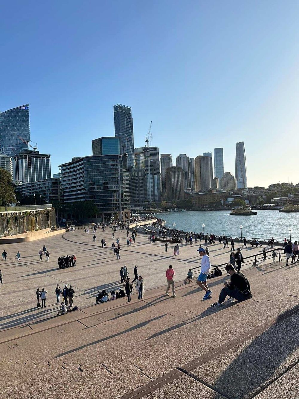Vibrant city skyline with modern skyscrapers and a bustling waterfront promenade in Sydney, Australia.