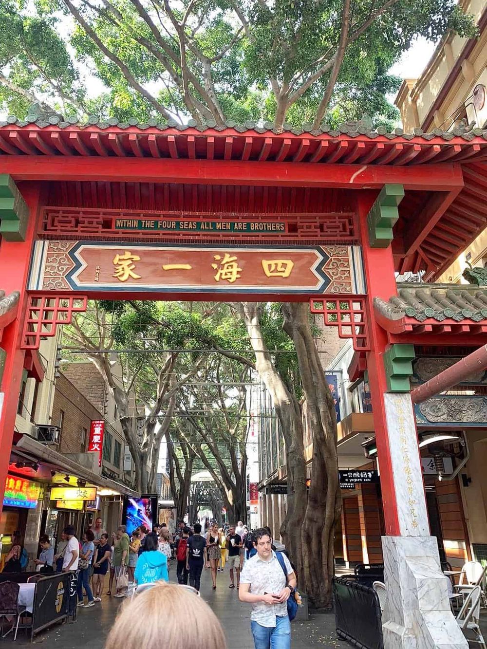 Traditional Chinese archway at Chinatown shopping district, vibrant street scene, diverse crowd, popular tourist destination.