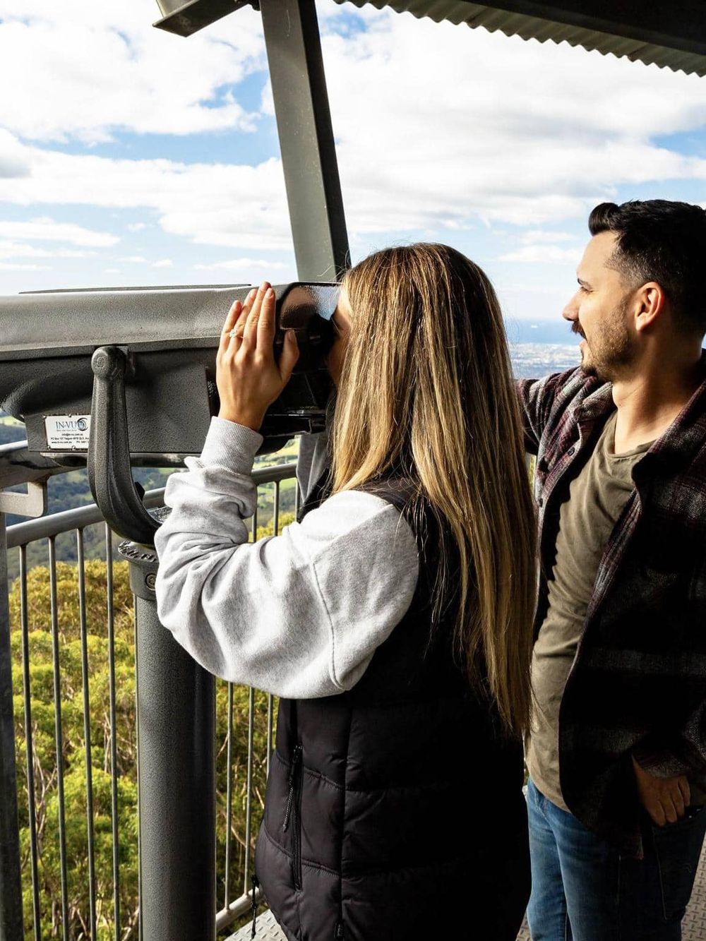 Sightseeing couples using binoculars at an observation deck, exploring scenic views and exploring outdoor adventures.