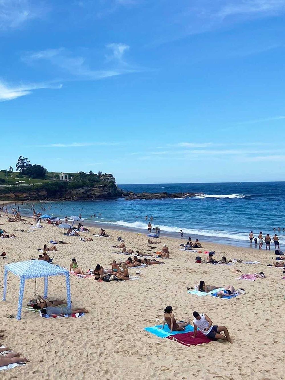Vibrant beach scene with people relaxing and swimming at a sunny coastal destination.