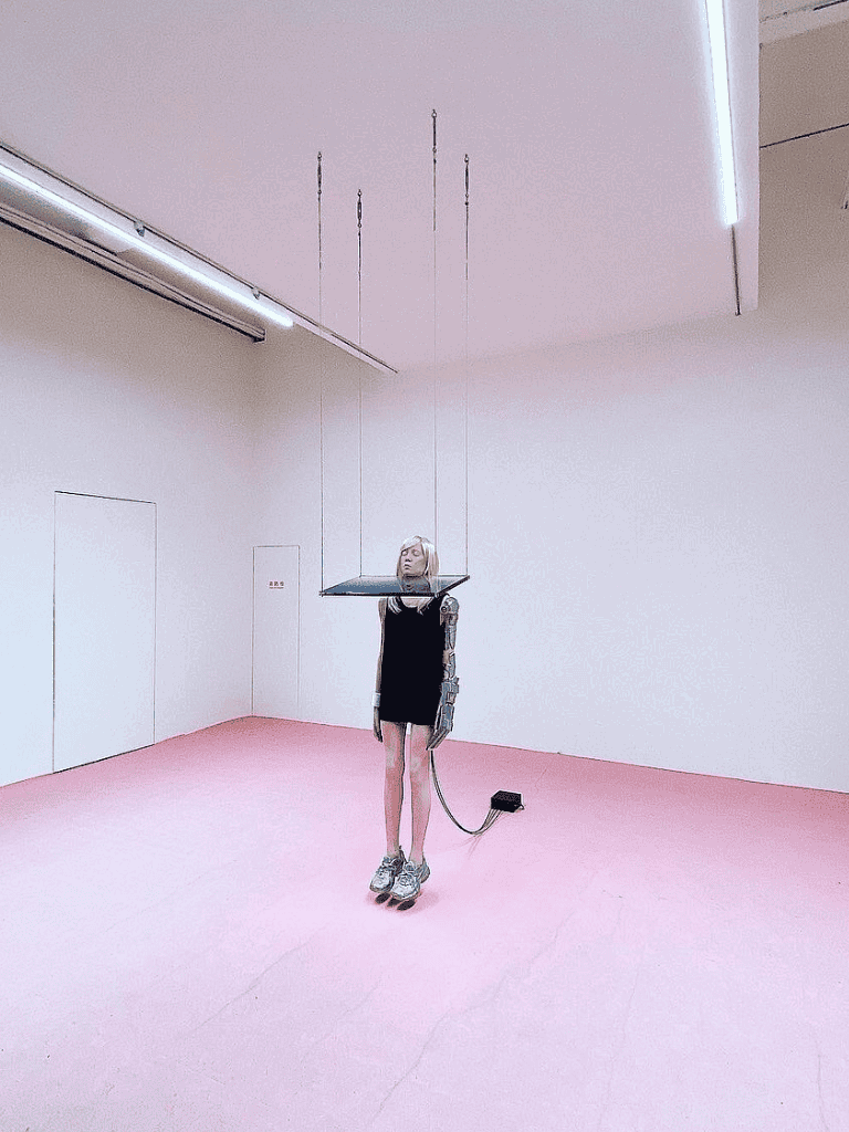 Robotic woman in futuristic art installation with pink floor at QuestForDirections.