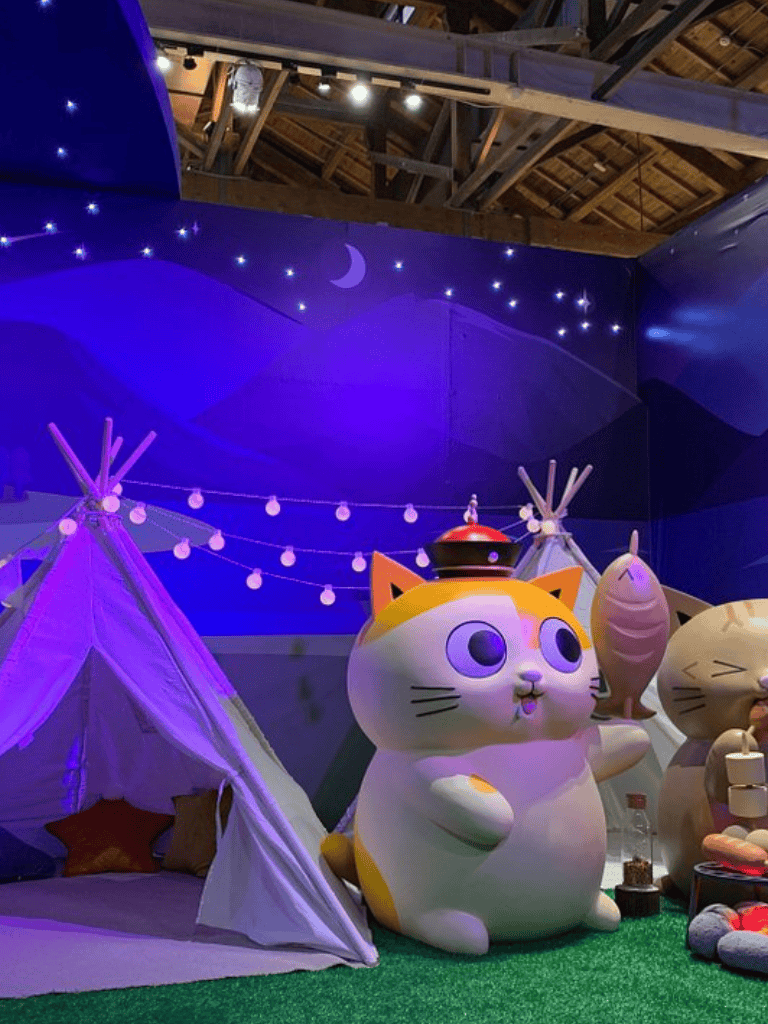 1. Large cute cat sculpture with fishing rod in whimsical themed space.
