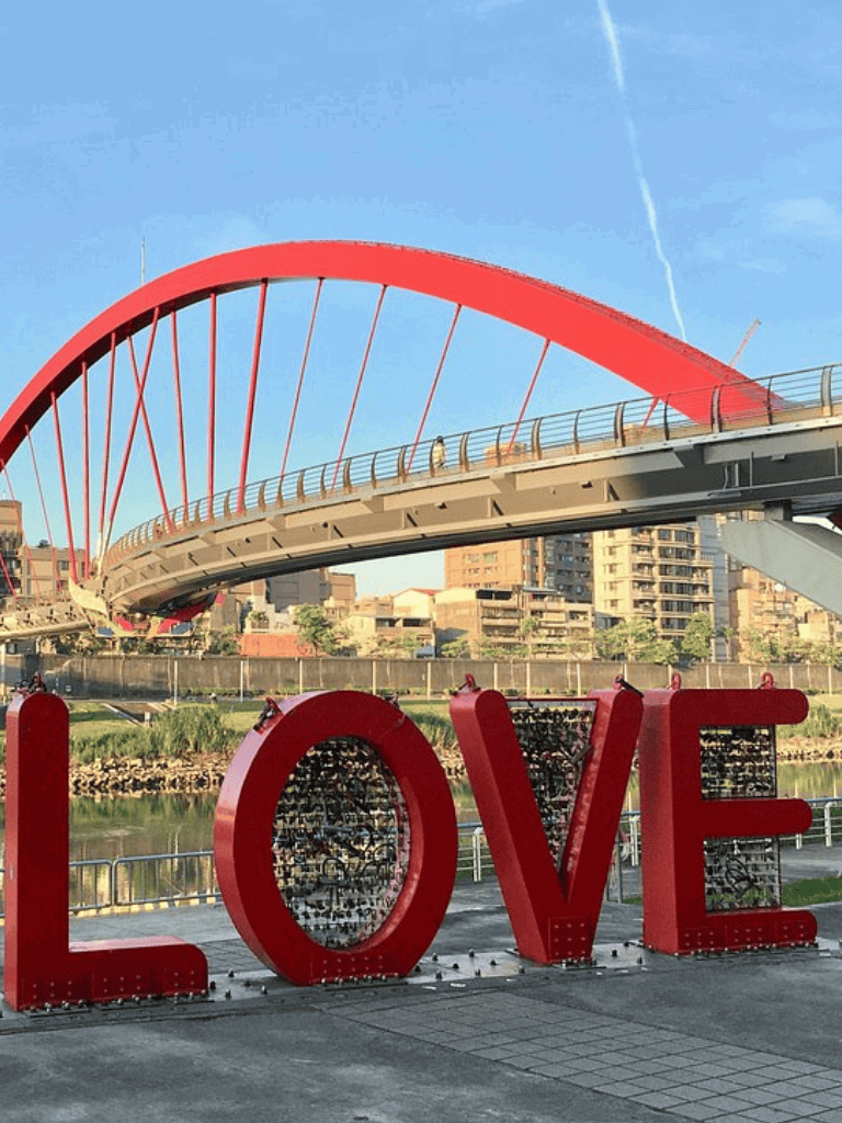 Red LOVE sculpture near Calvary Bridge in Cairo with city skyline in the background.