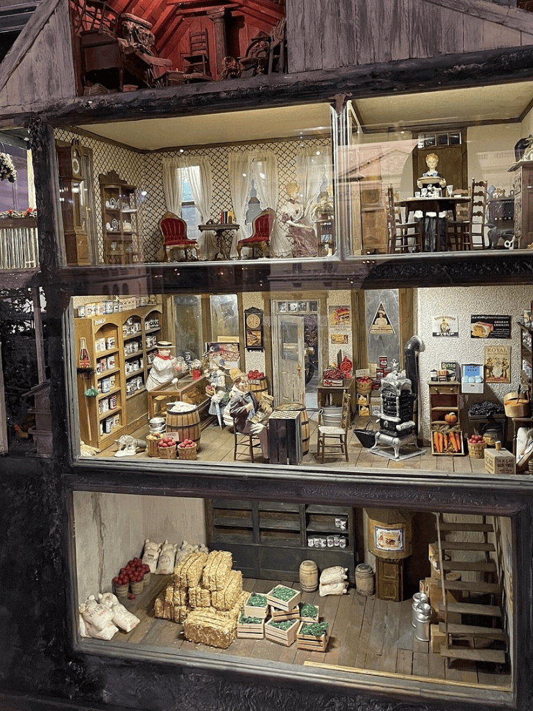 Miniature dollhouse with vintage furniture and items, showcasing detailed interior decor and collectibles.
