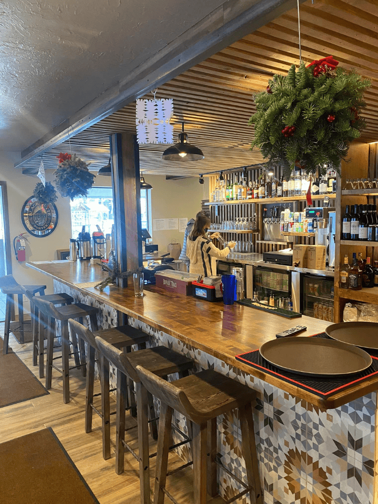 Cozy bar interior with Christmas decorations and wooden accents, welcoming atmosphere for dining and drinks.