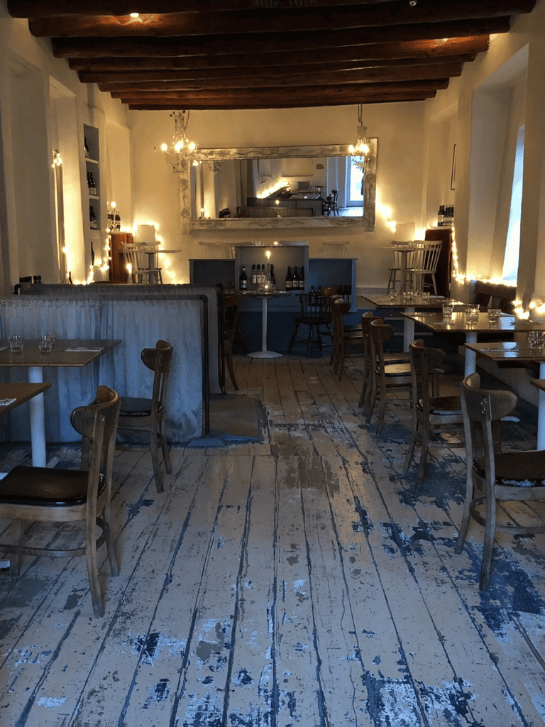 Cozy rustic dining room with string lights, wooden beams, and vintage decor for a warm, inviting atmosphere.