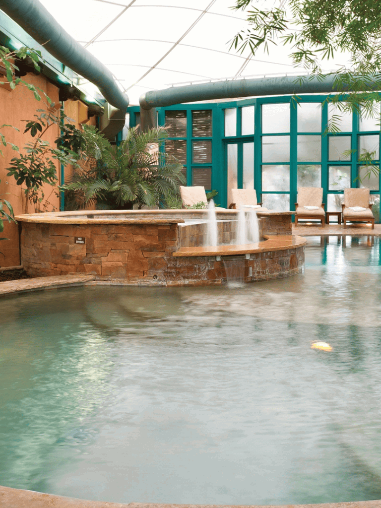 Serene indoor hot spring with waterfalls, lush greenery, and comfortable seating at QuestForDirections.
