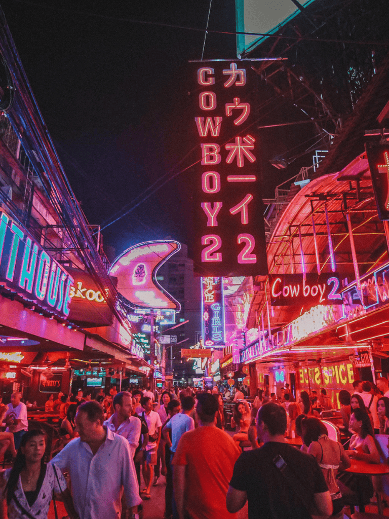 Neon nightlife street with colorful signs and crowds, popular urban destination for socializing and entertainment.