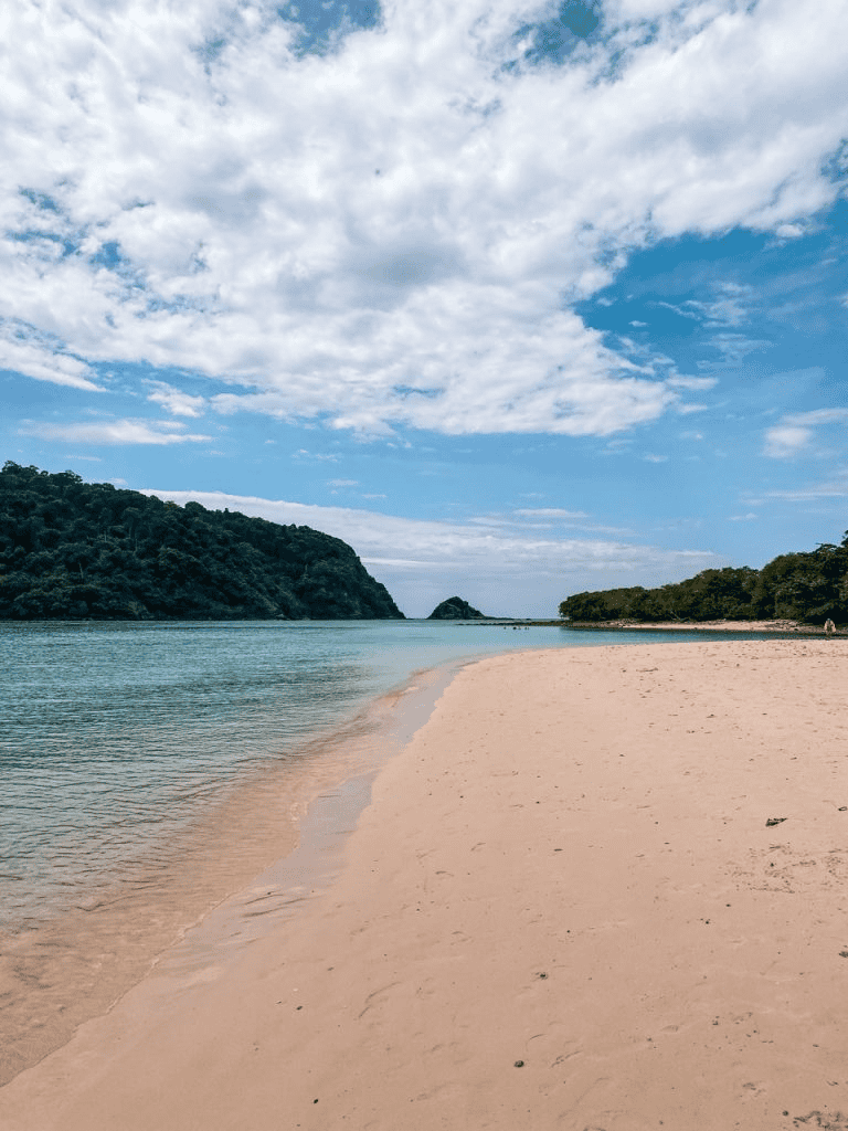 Secluded beach with clear waters and lush green islands, perfect for travel and adventure seekers.