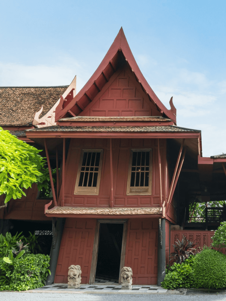 Intricate traditional Thai temple with vibrant red wood and ornate carvings.
