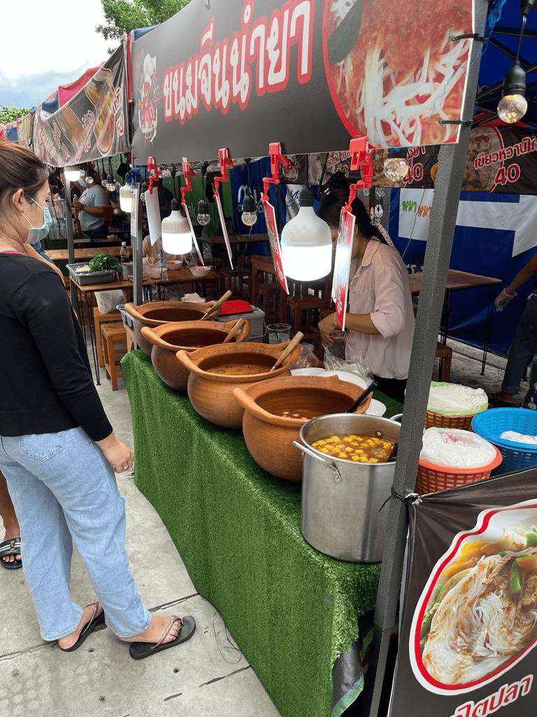 Spicy Thai soup and traditional dishes at QuestForDirections food stall in a busy outdoor market.