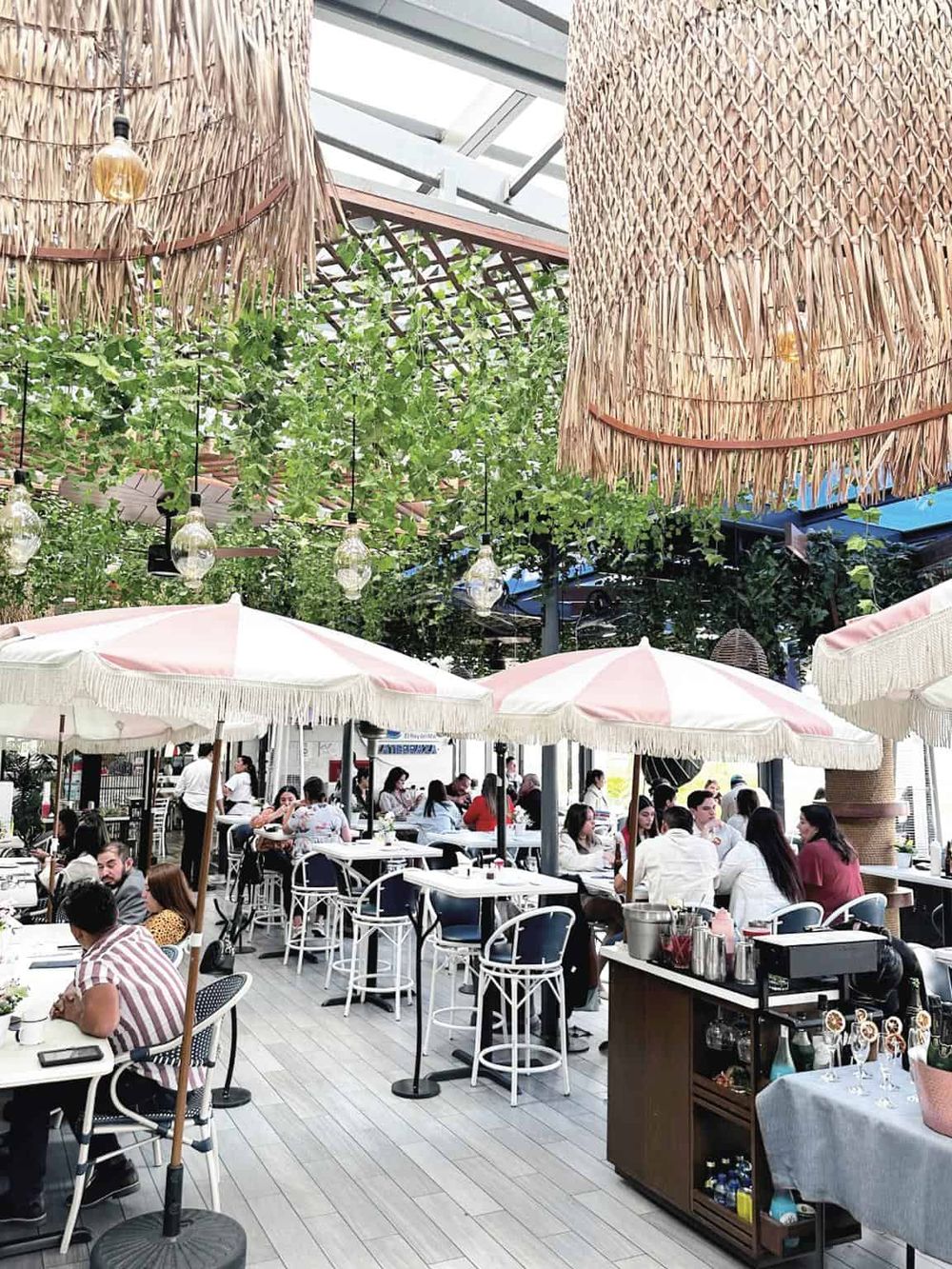 Outdoor dining at a vibrant restaurant with lush greenery and cozy umbrellas, perfect for socializing and enjoying delicious food.