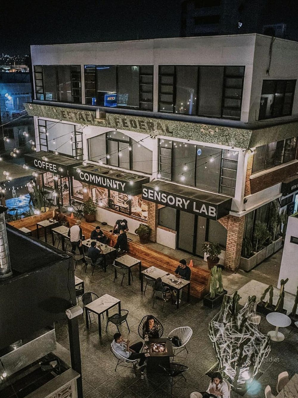 Modern coffee shop with outdoor seating and ambient lighting at night, perfect for community gathering and sensory experiences.