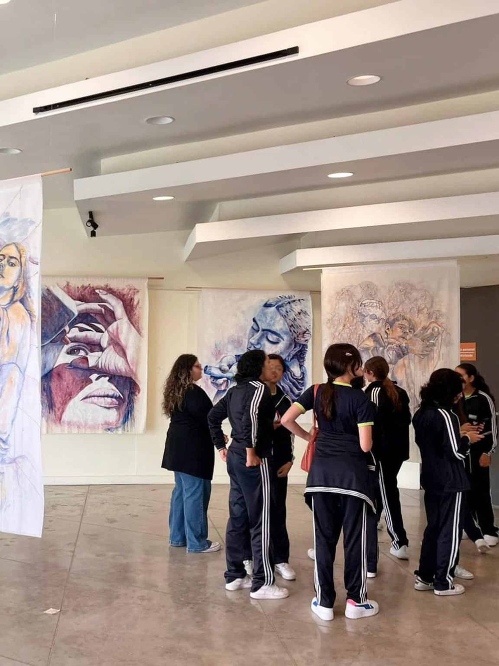 Colorful murals and young students viewing artwork at QuestForDirections art exhibit.