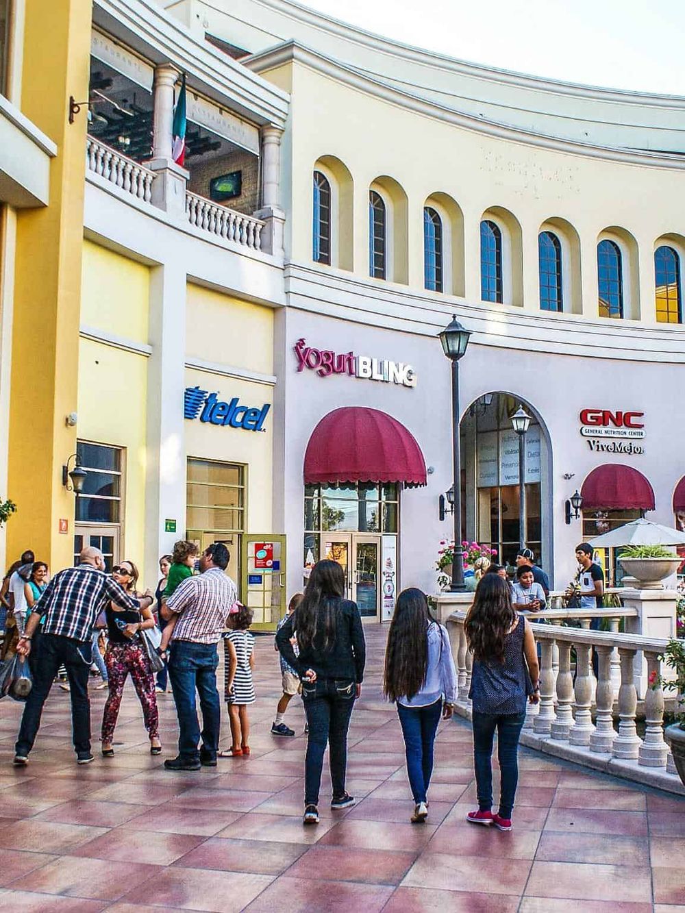 Vibrant shopping mall exterior with diverse shoppers and popular retail stores, perfect for an engaging urban shopping experience.