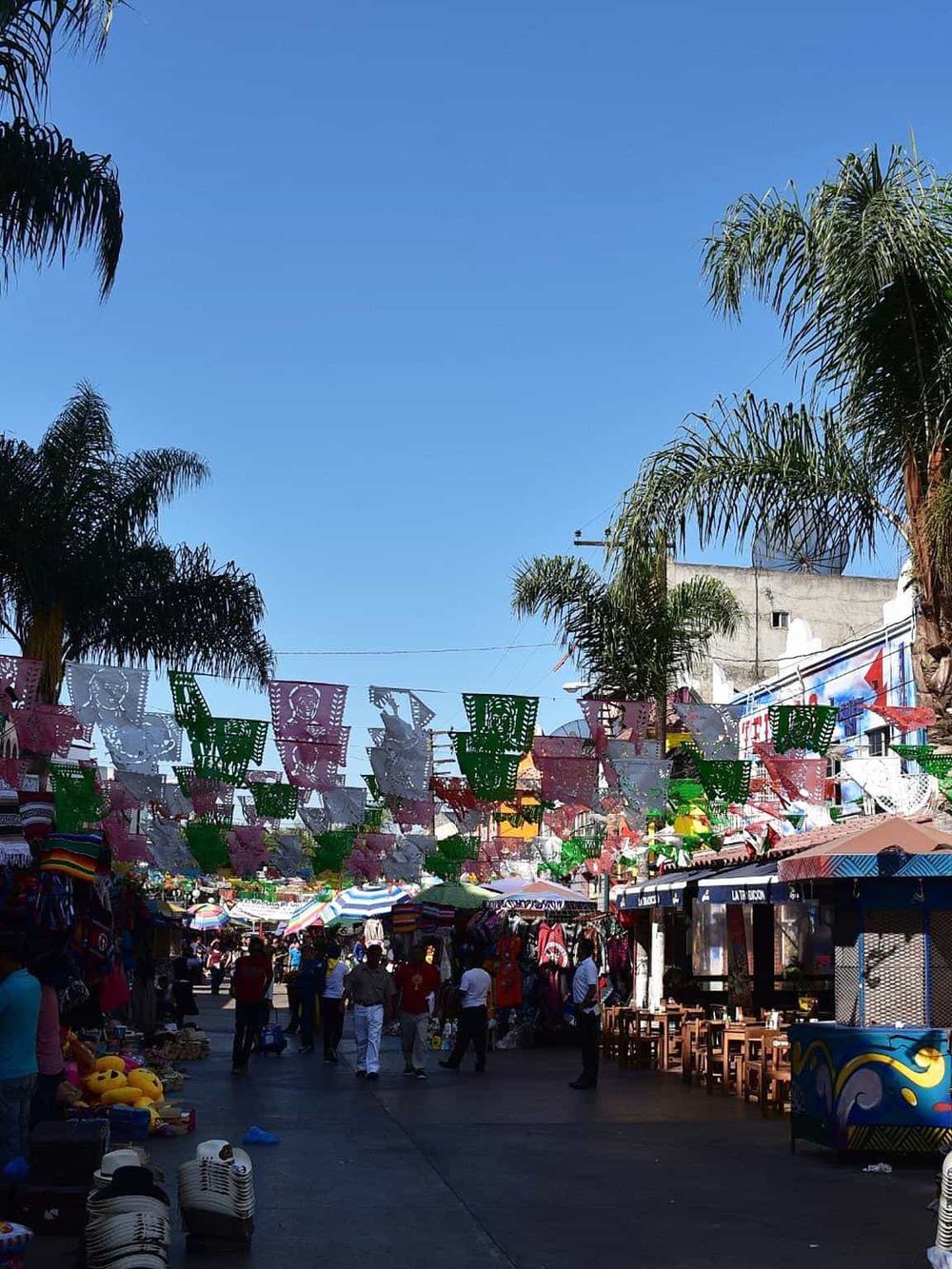 Colorful traditional Mexican papel picado decorations hanging over a bustling street market.