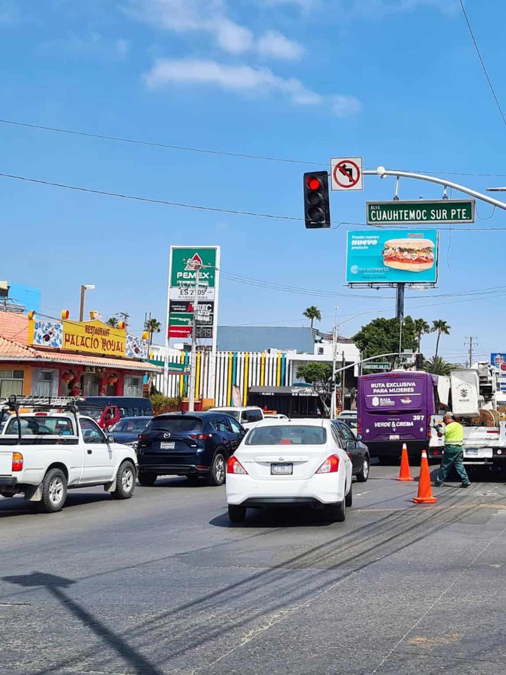 Busy city street with traffic signals, billboards, and vehicles, showcasing urban navigation and direction signs.