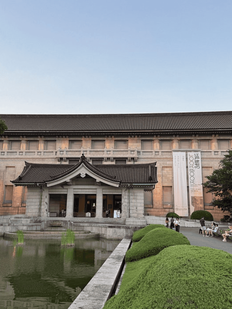 Ancient Japanese building at the Japan Folk Art Museum with pond and greenery.