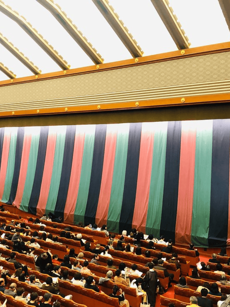 Bright theater stage with colorful curtains and an audience attending a conference or event.