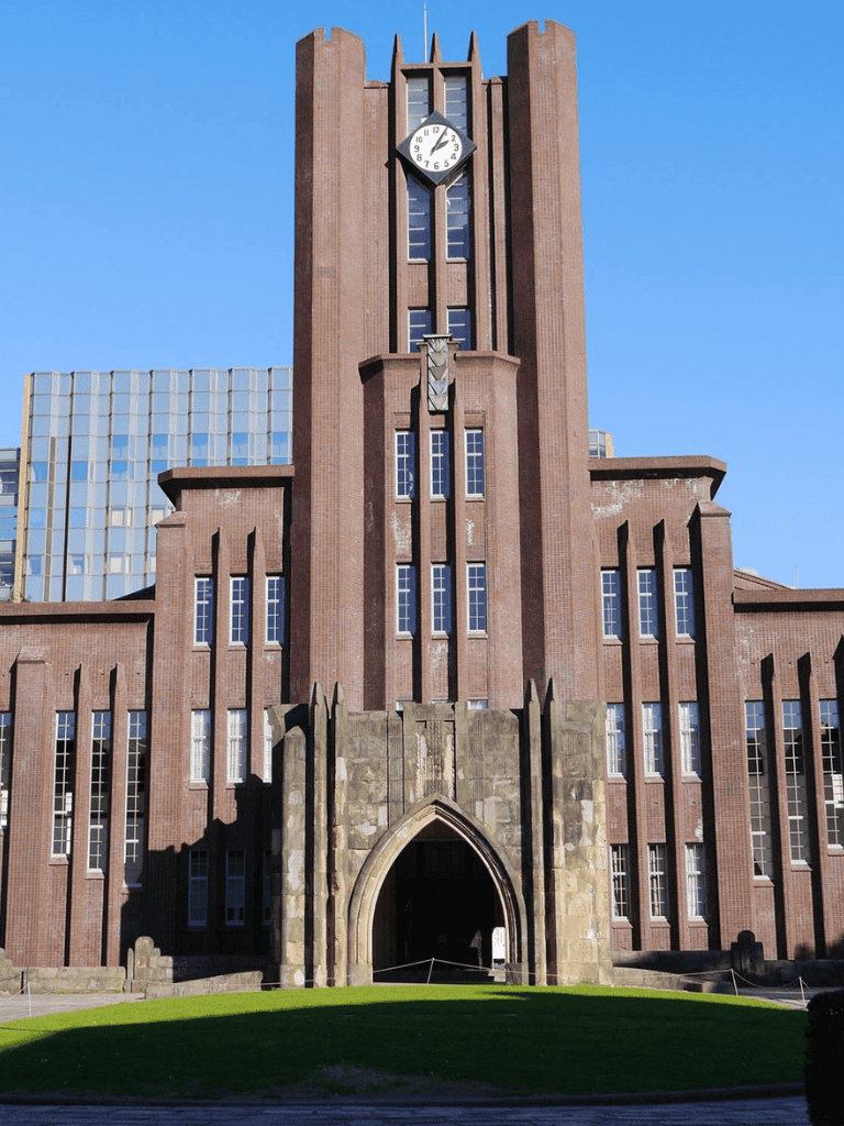 Historic university clock tower with Gothic architecture, central to academic campus, with clear blue sky.